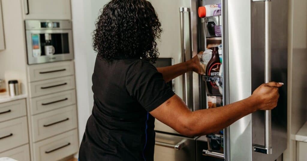 Newborn Care Specialist reaches in to open fridge