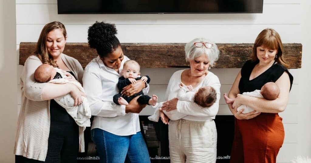 Four women stand holding babies