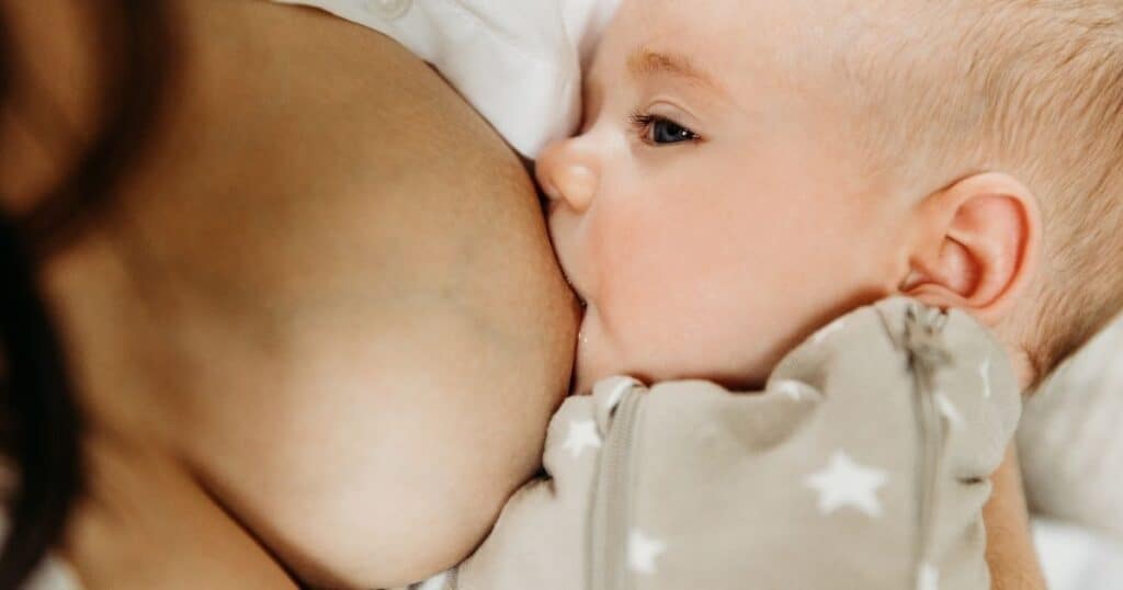 Baby latches onto mother's breast while nursing