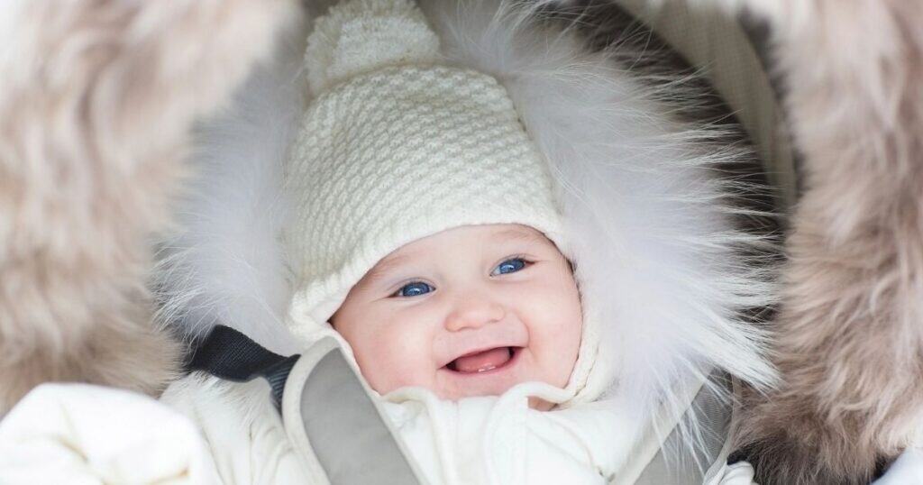 Baby in hat is bundled up and smiling