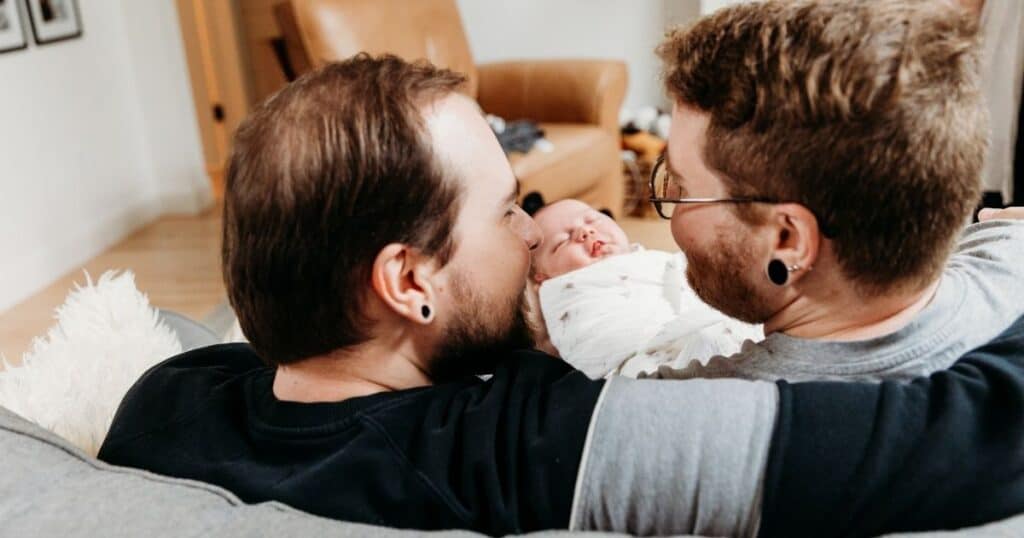 Parents look at eachother while holding baby between them