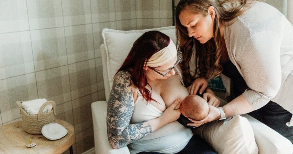 Postpartum doula helps mother and baby latch during a breastfeeding session