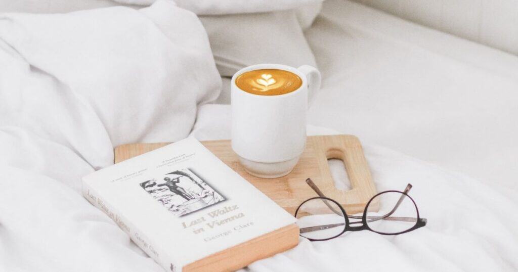 Coffee, journal and glasses sit on bed