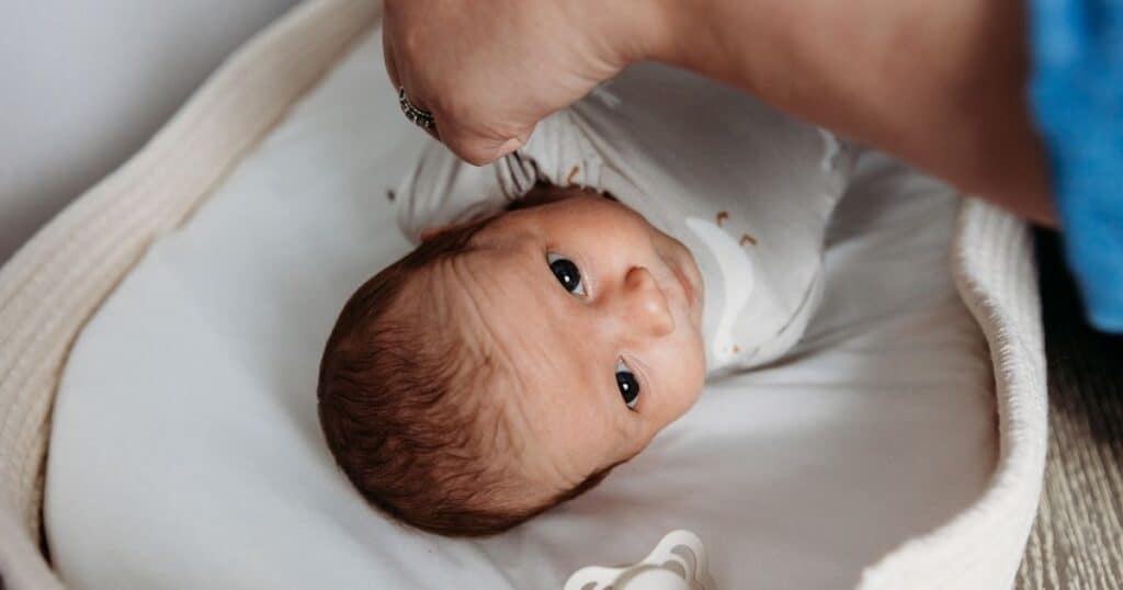 Postpartum Doula dresses baby in goose outfit on changing table