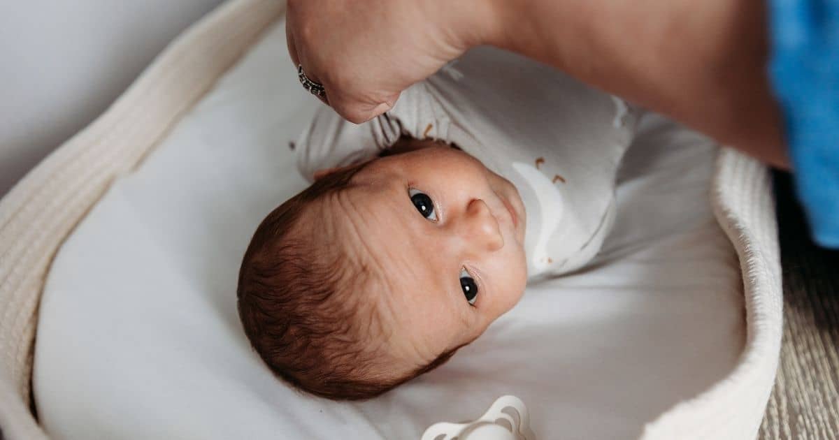 Postpartum Doula dresses baby in goose outfit on changing table