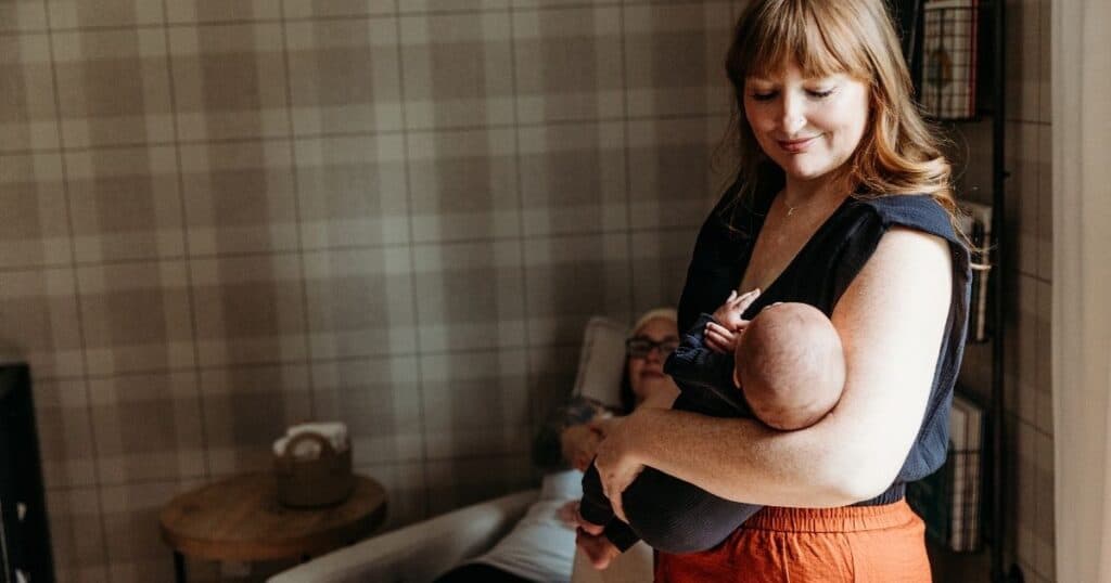 Postpartum Doula rocks baby while mom rests in background