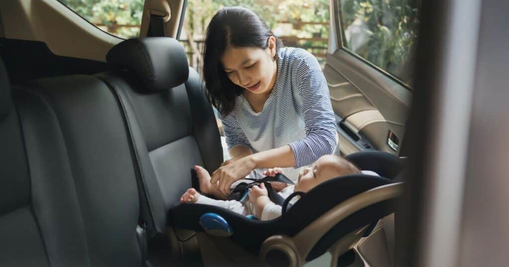 mom placing infant in car seat