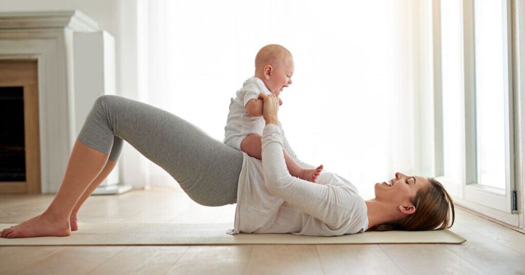 Mom works out on yoga mat with baby sitting on her stomach