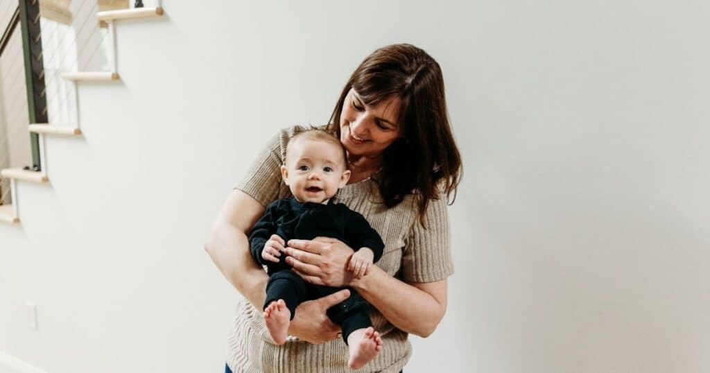 Mother holds baby and looks down at them