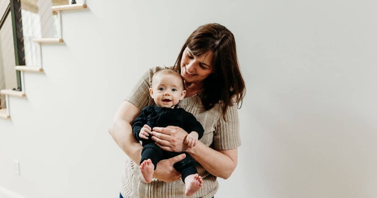 Mother holds baby and looks down at them