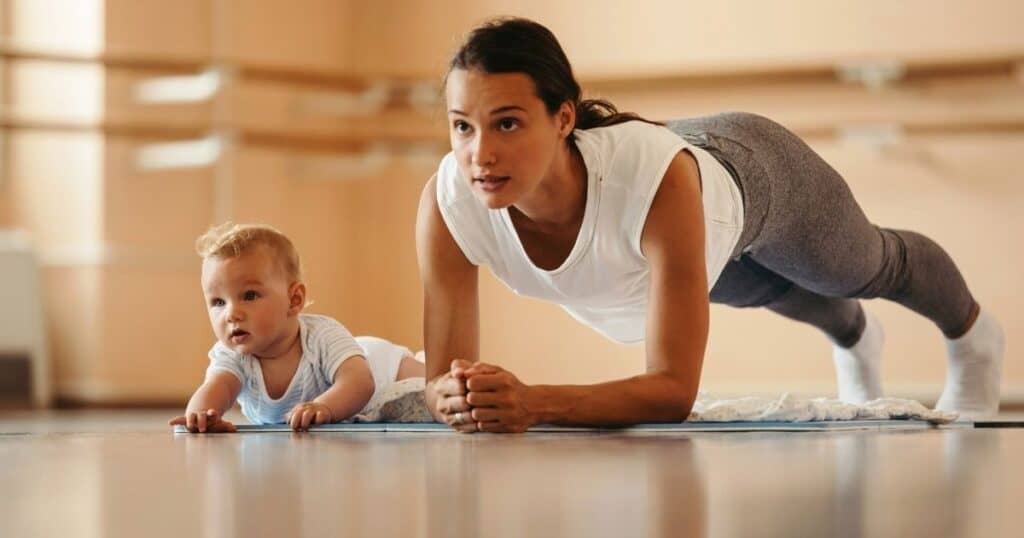 Mom hold plank while baby does tummy time next to her