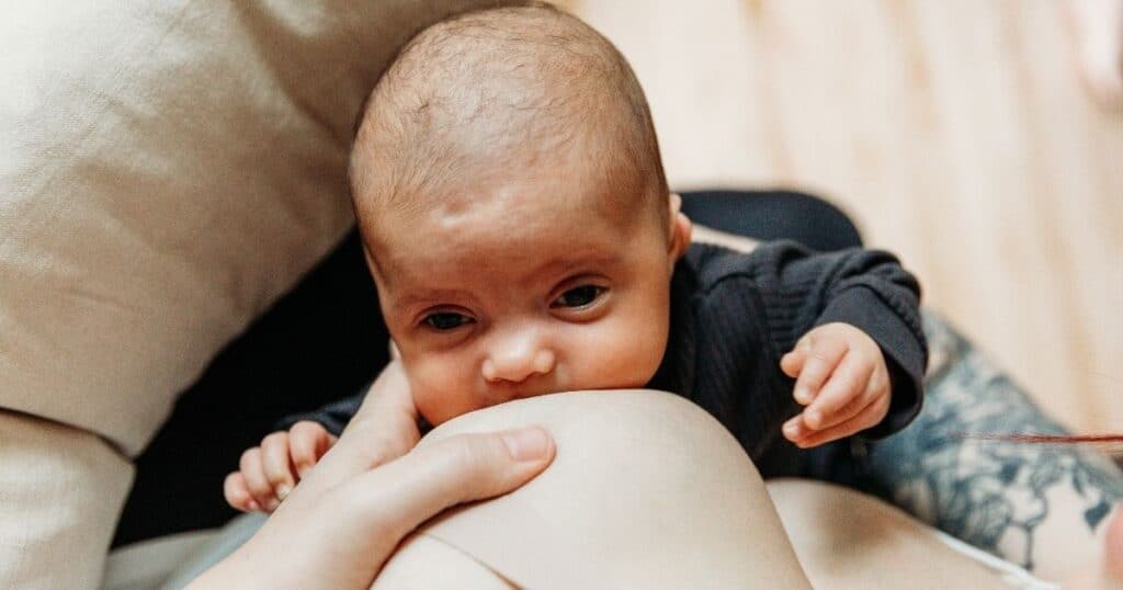 Baby looks up at mother while latched to breast
