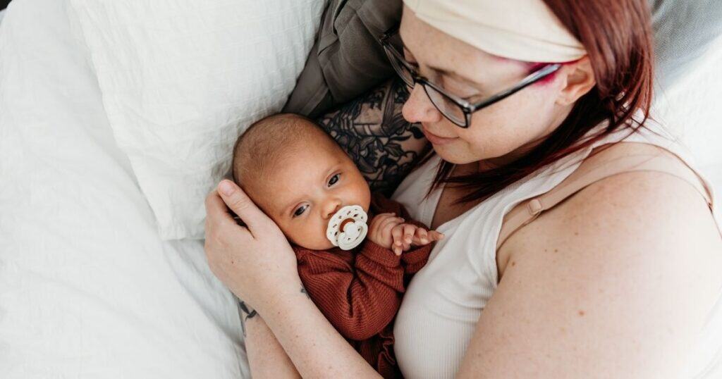 Mom and baby cuddle in bed together