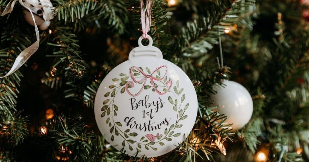 Baby's first Christmas ornament hands on tree