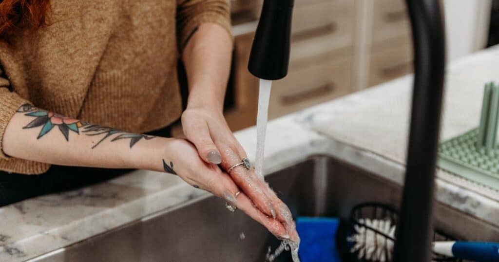 Postpartum Doula washes hands in kitchen sink