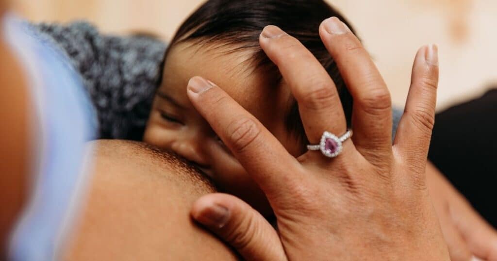 nurses baby from breast while rubbing their third eye