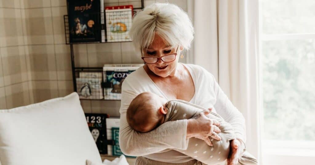 Postpartum Doula cradles baby while standing in nursery