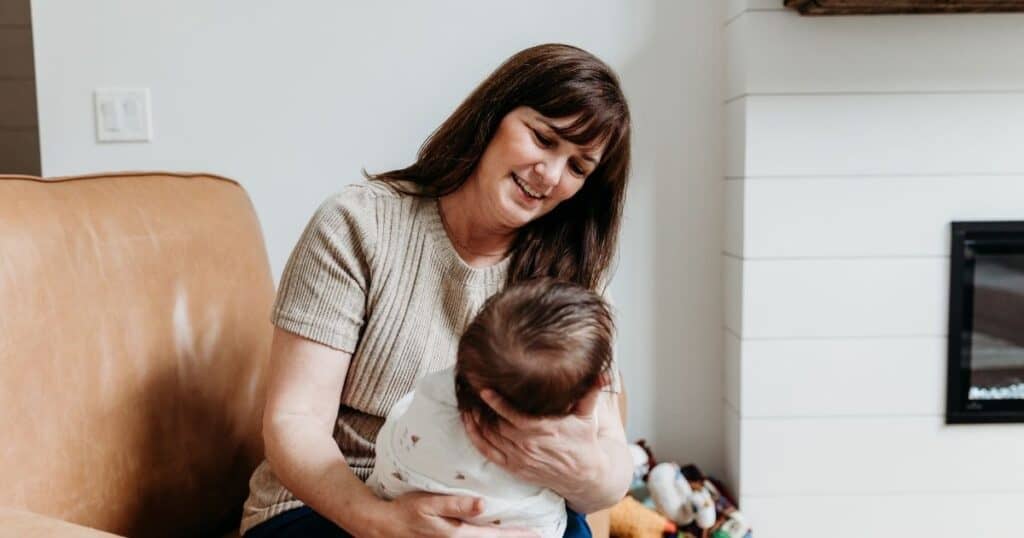 Postpartum Doula holds swaddled baby facing her