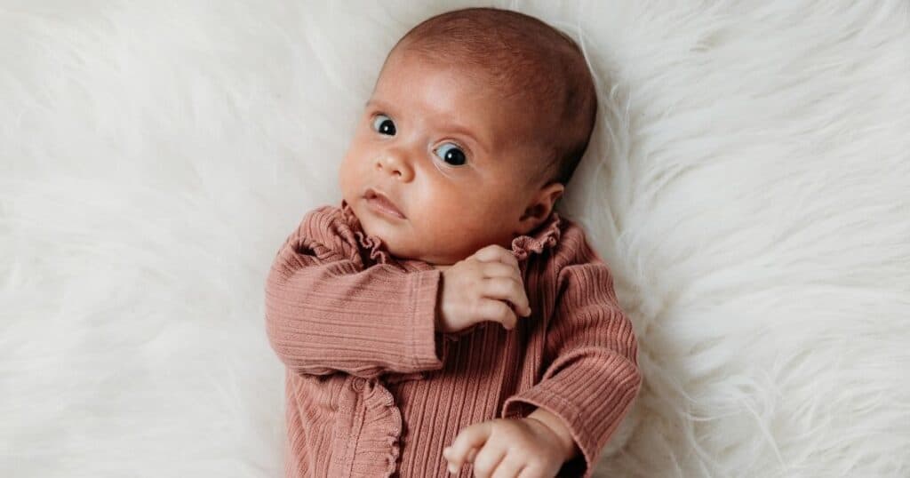 Baby looks skeptically into camera with eyebrow raised