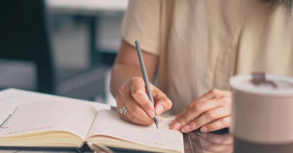 Woman writes with pen in an open journal