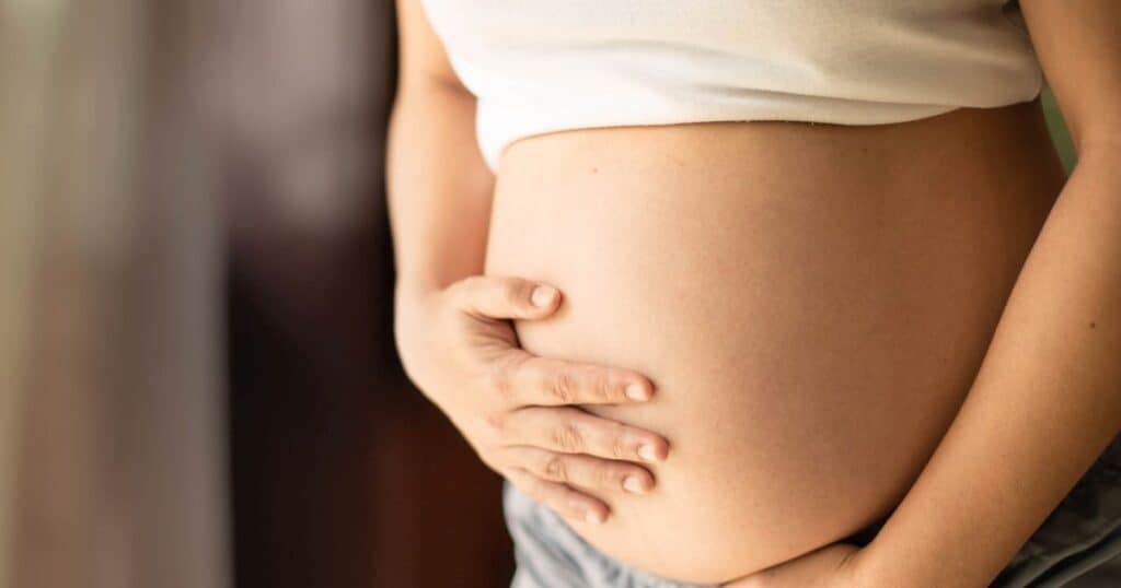 Pregnant woman cradles her stomach