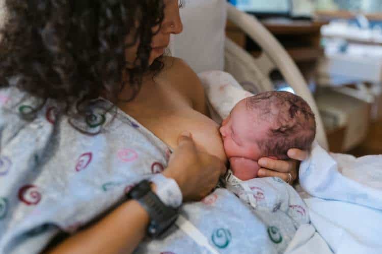 breastfeeding newborn in hospital bed