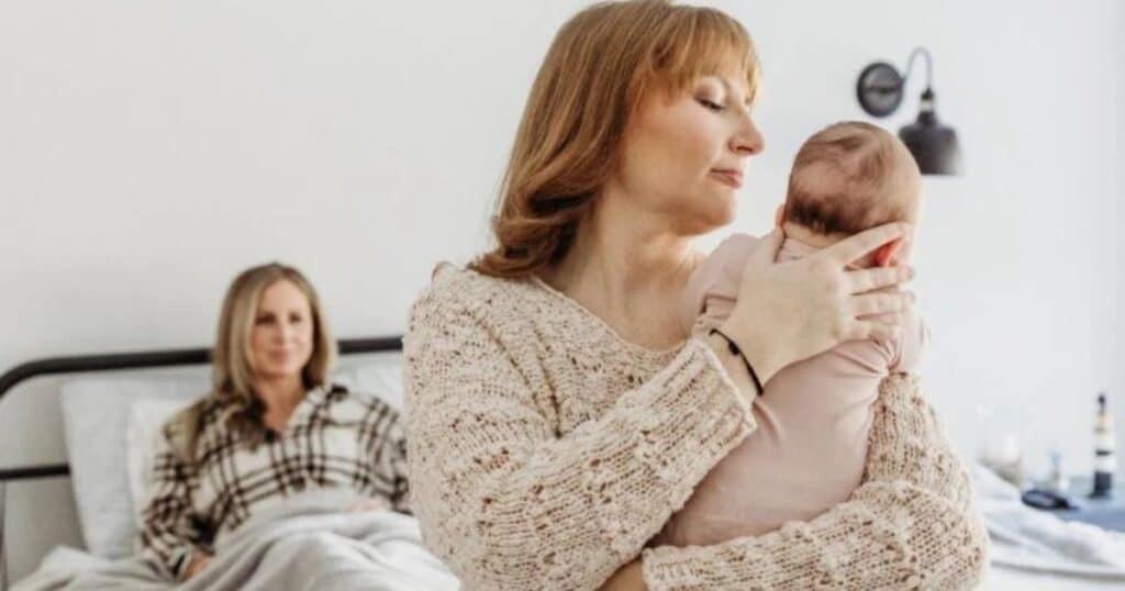 night nurse holds baby while mom resting in bed