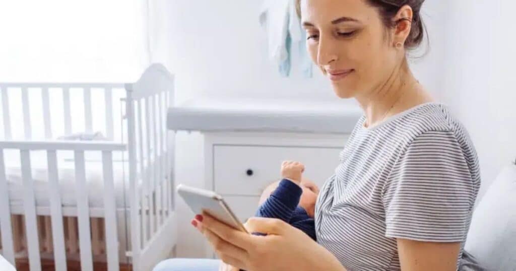 new mom watching online newborn care class on her phone while holding baby