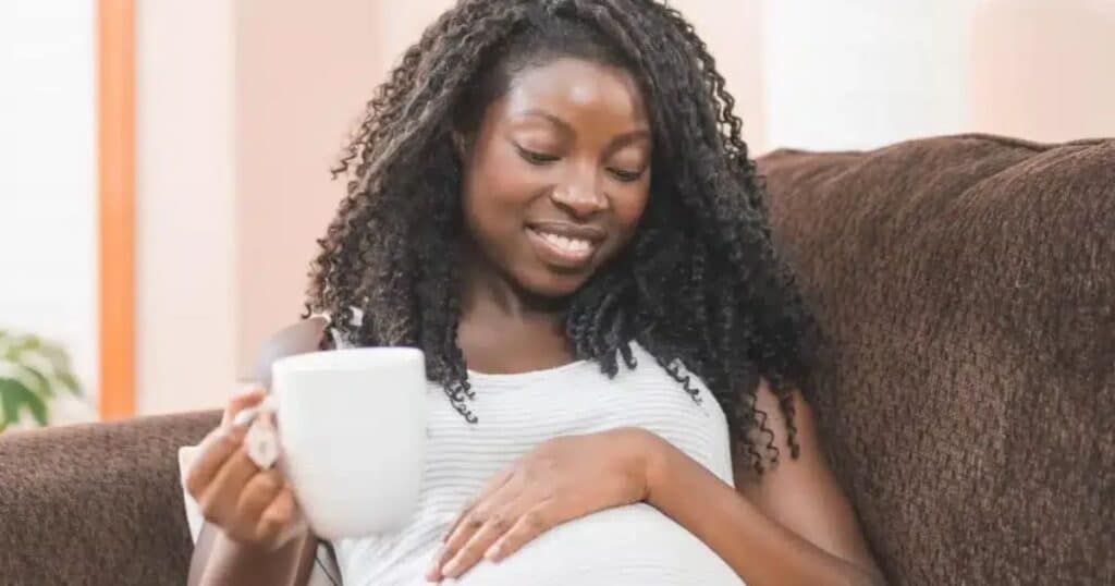 pregnant woman with tea looking at belly