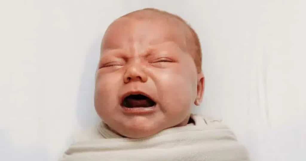 teething newborn crying in swaddle wrap