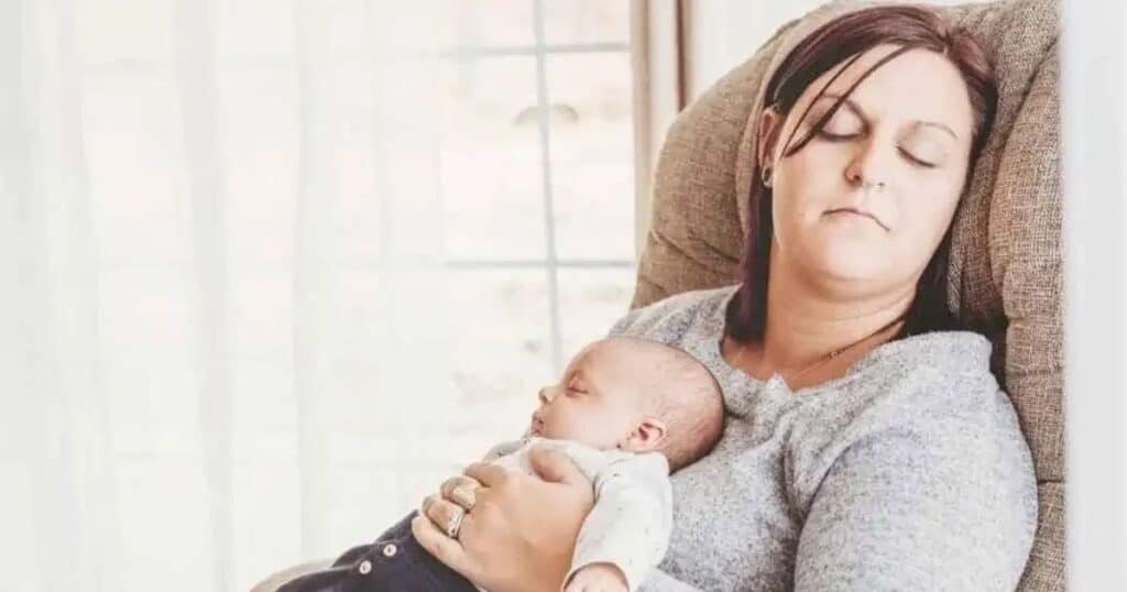 sleep deprived new mom sleeping in chair with baby on chest