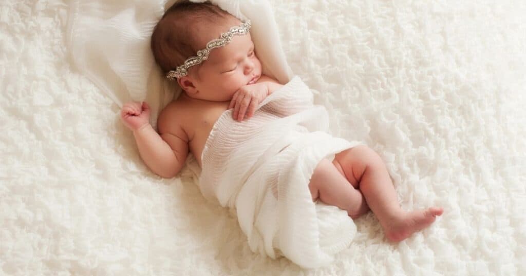 Baby girl sleeps in toga and head piece