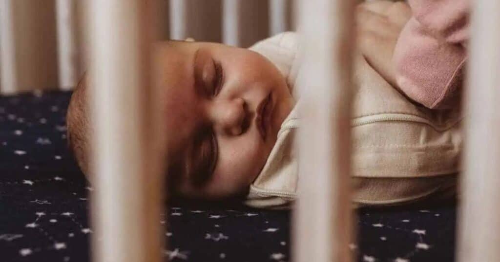 baby sleeping in crib with swaddle
