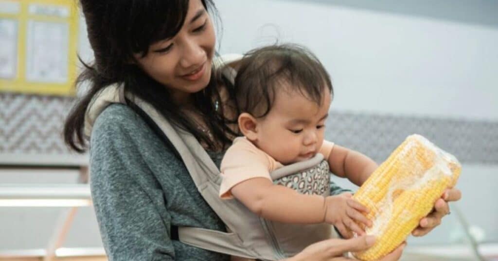 mom wearing baby in sling at grocery store