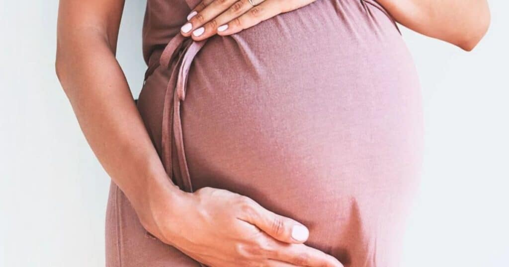 Woman caressing her pregnant belly.