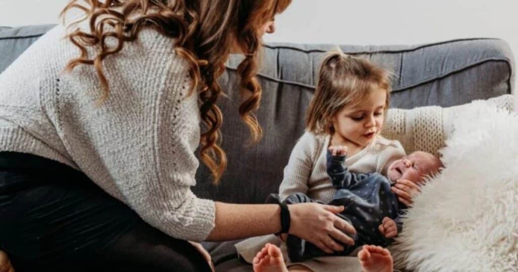 introducing toddler to newborn sibling on sofa