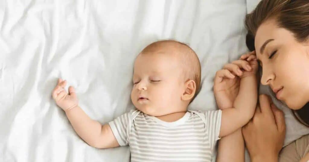 sleep deprived mom and baby sleeping on bed
