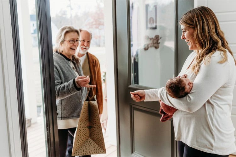 grandparents greeting new mom at front door after bringing baby home from hospital