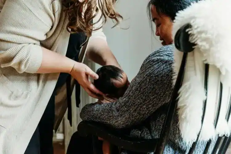 newborn care specialist helping new mom with cluster feeding newborn baby