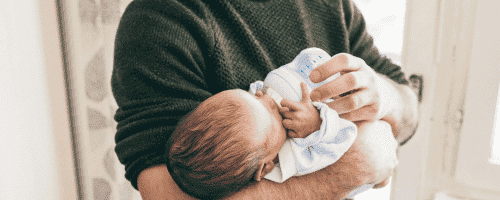 parent feeding baby bottle