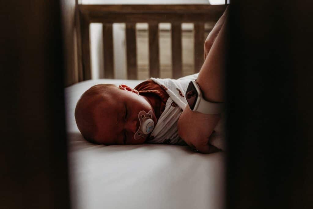 night nurse placing sleeping baby in crib during overnight newborn care shift.
