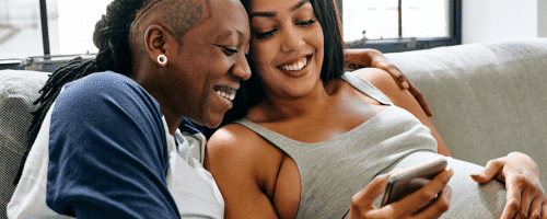 pregnant couple on couch laughing