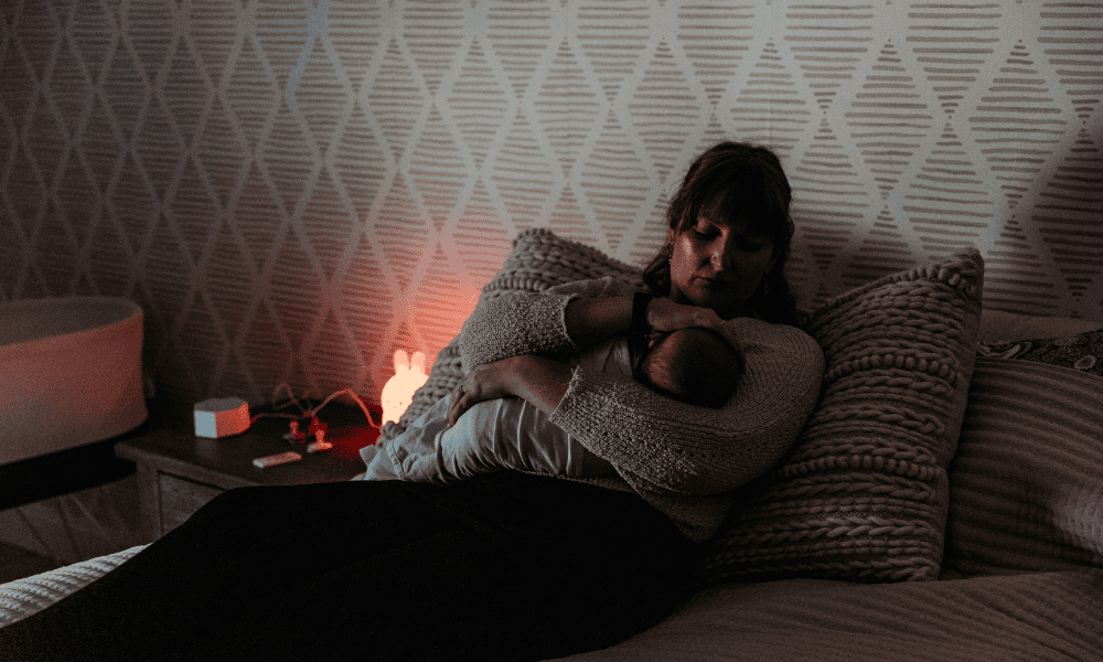 Hiring a Postpartum Doula for Overnight Newborn Care- a doula resting on a bed with a newborn