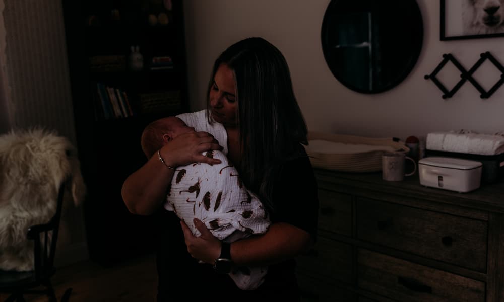 Doula comforts baby in a dark room