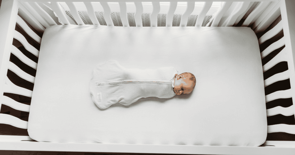 baby sleeping safely swaddled in a crib, following aap safe sleep guidelines
