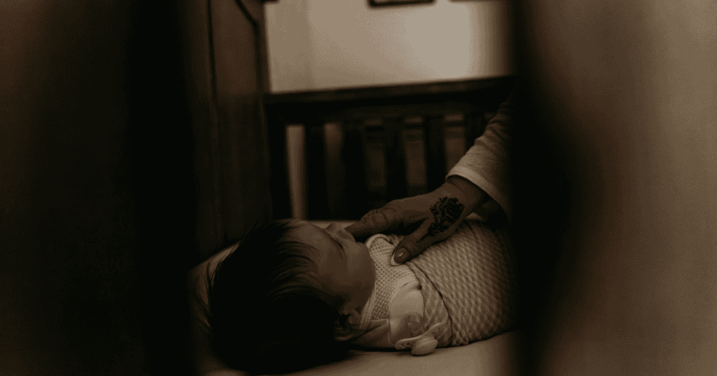newborn in crib with hand on chest