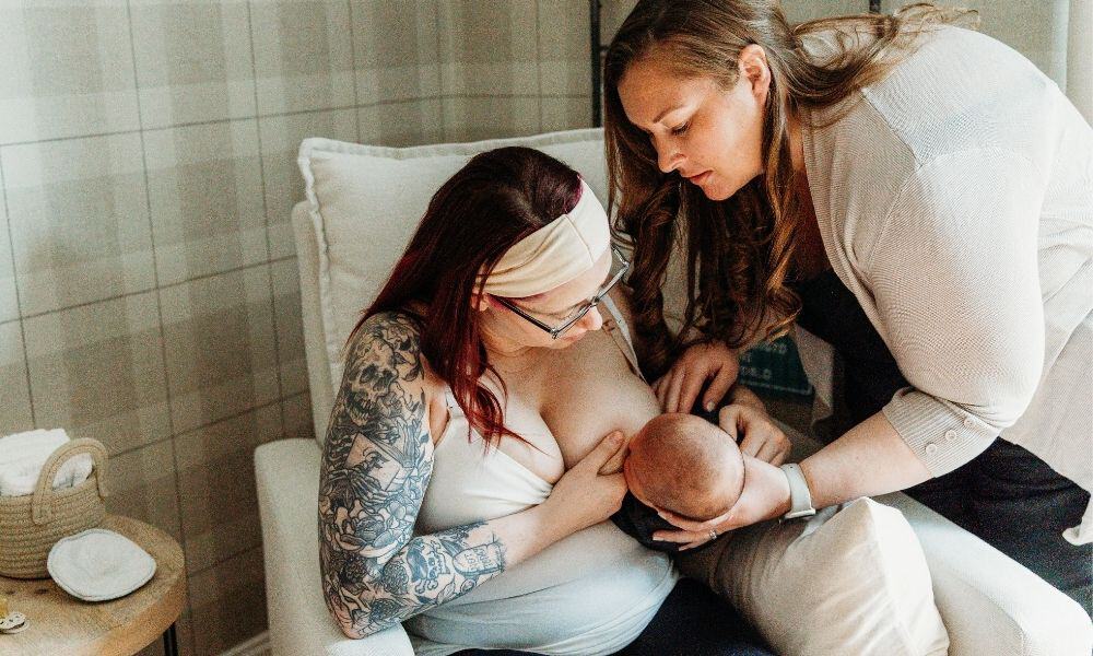 Postpartum Doula helps mom breastfeed baby
