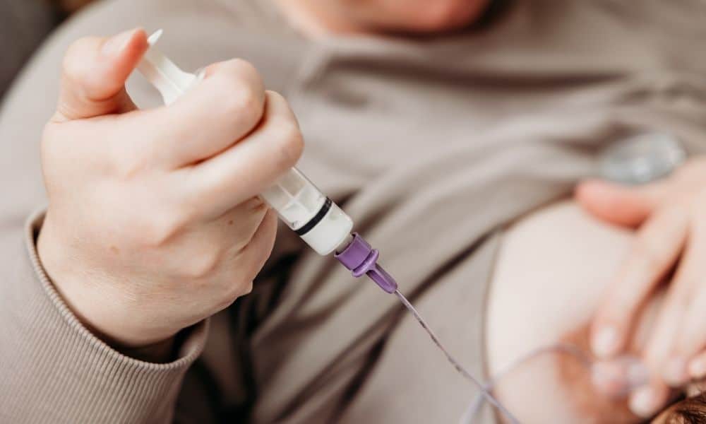 New adoptive mother syringe feeding newborn baby with donor milk or formula.