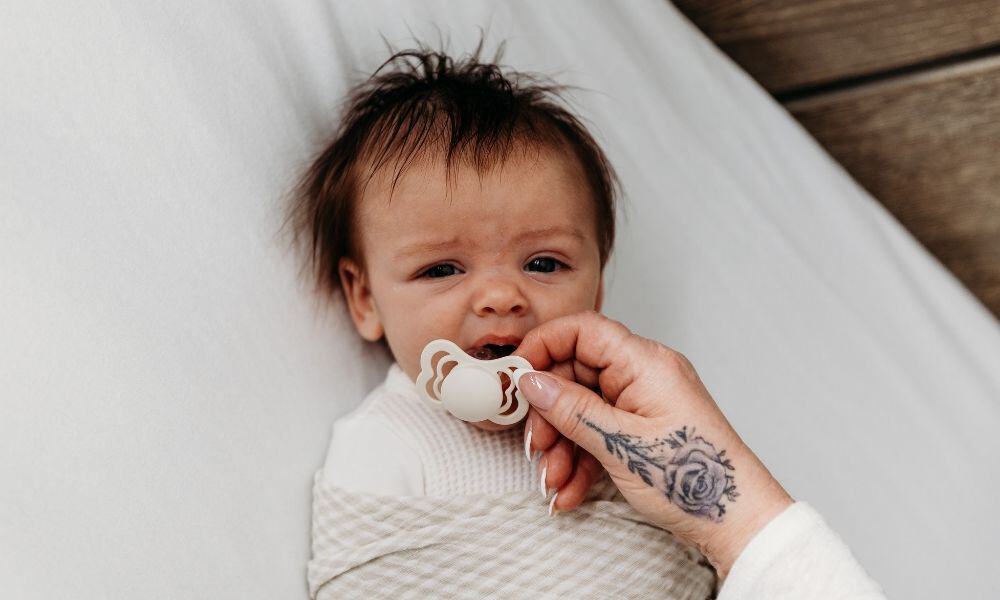 Awake baby being offered pacifier