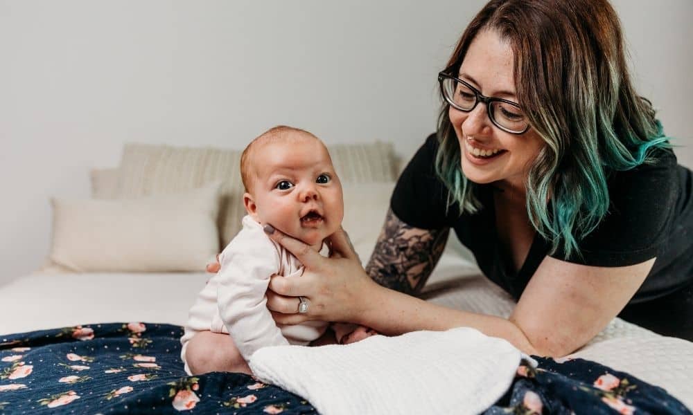 Postpartum Doula holds newborn on bed